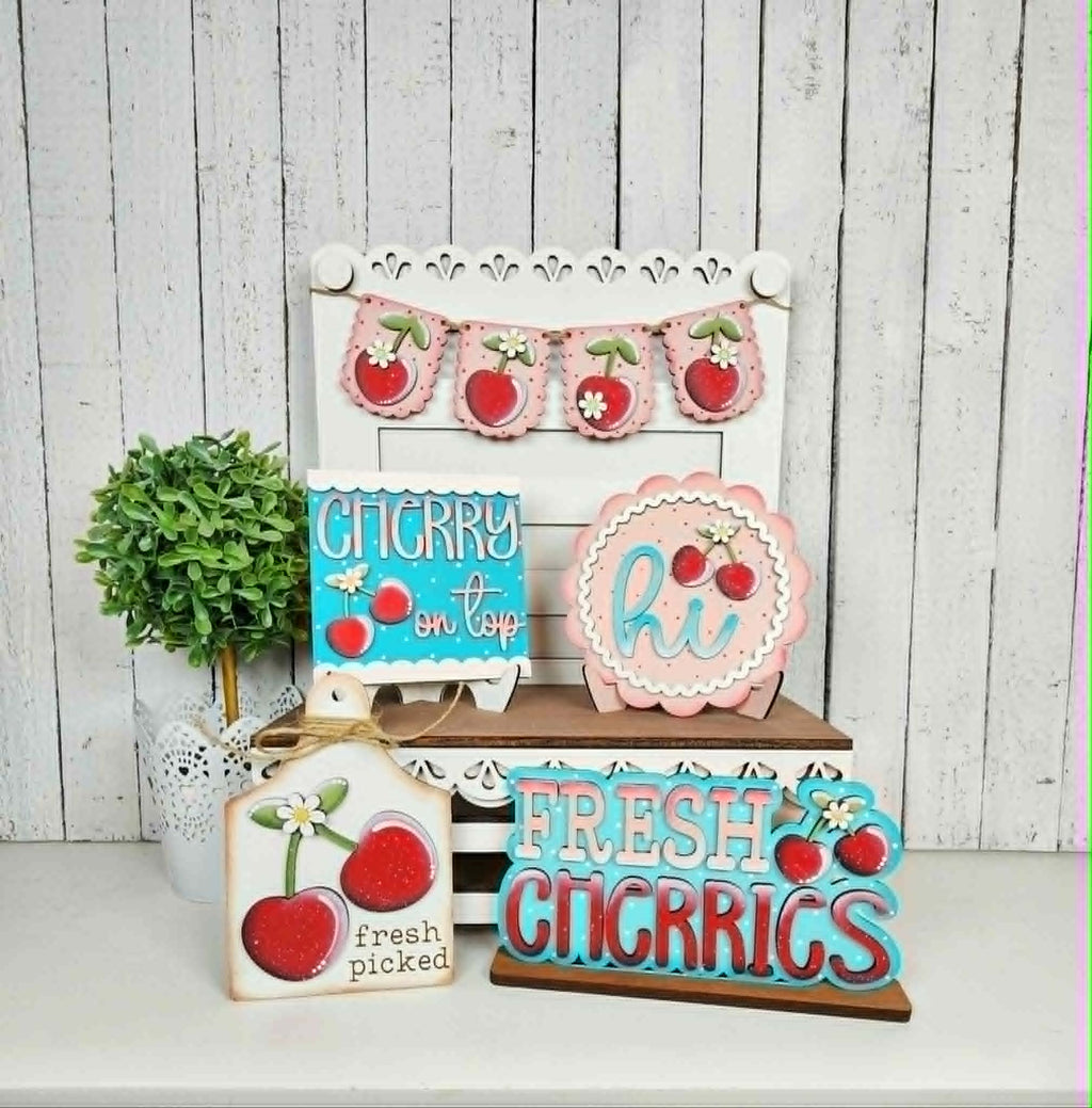 Decorative signs with cherry designs on a white surface and wooden background