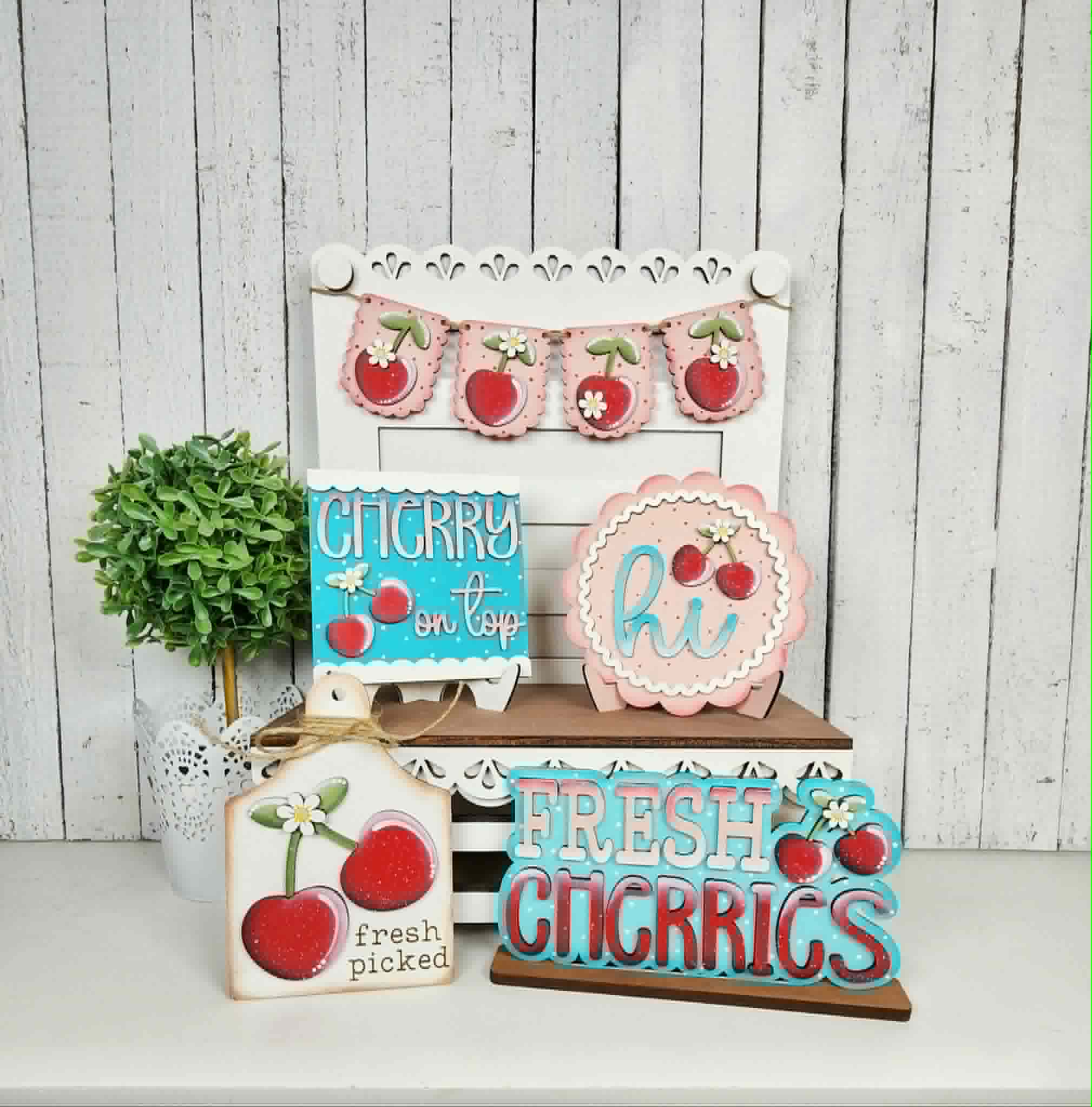 Decorative signs with cherry designs on a white surface and wooden background