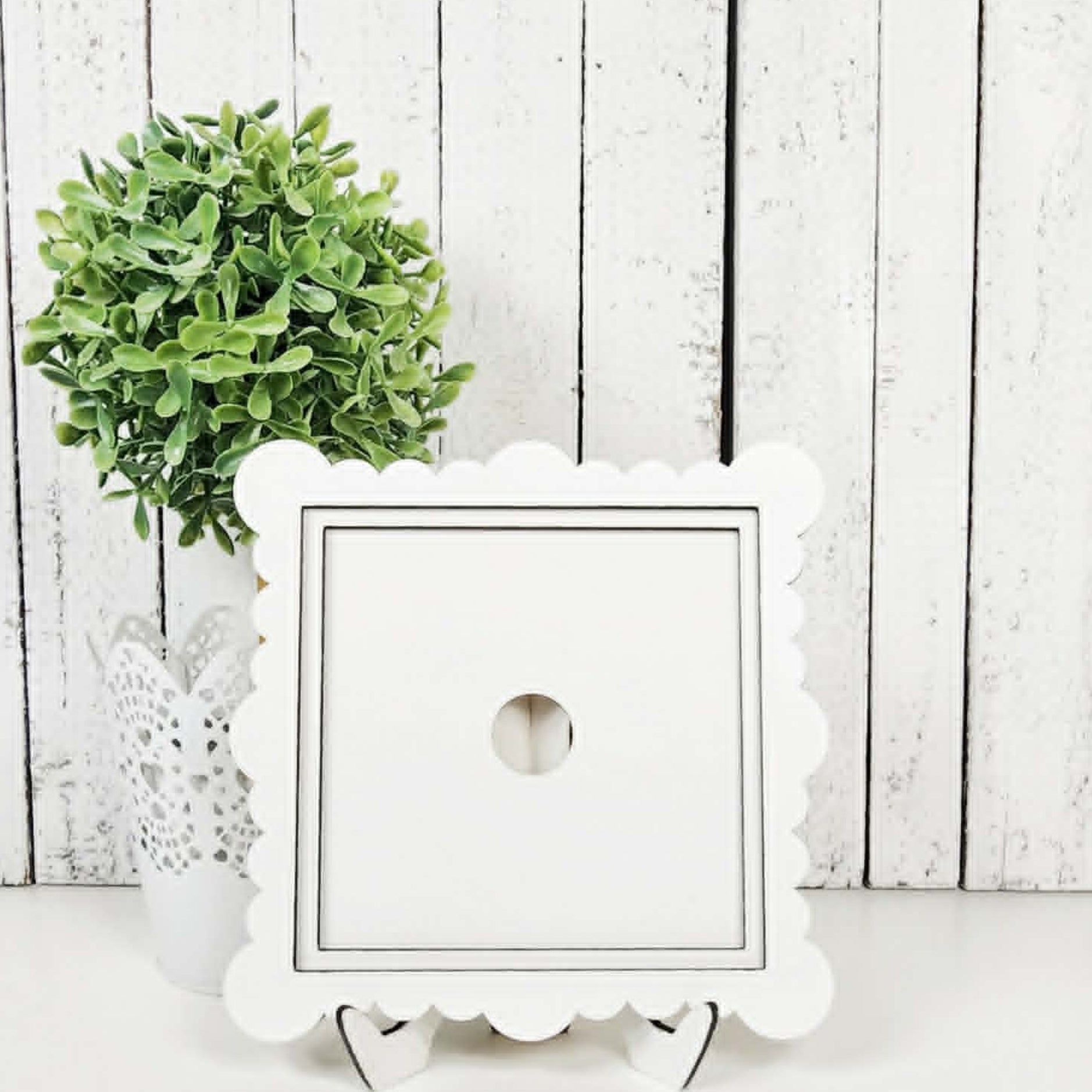 White decorative box with scalloped edge on a white surface with a wooden background