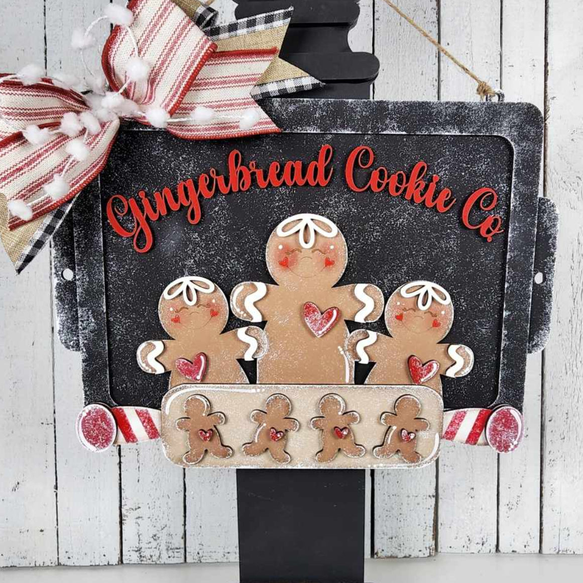 Decorative sign with gingerbread men and a bow on a wooden background