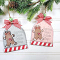 Two Christmas ornaments with gingerbread men designs hanging on a branch.