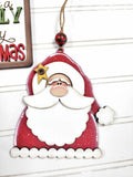 Decorative Christmas ornament with a smiling Santa Claus on a wooden background.