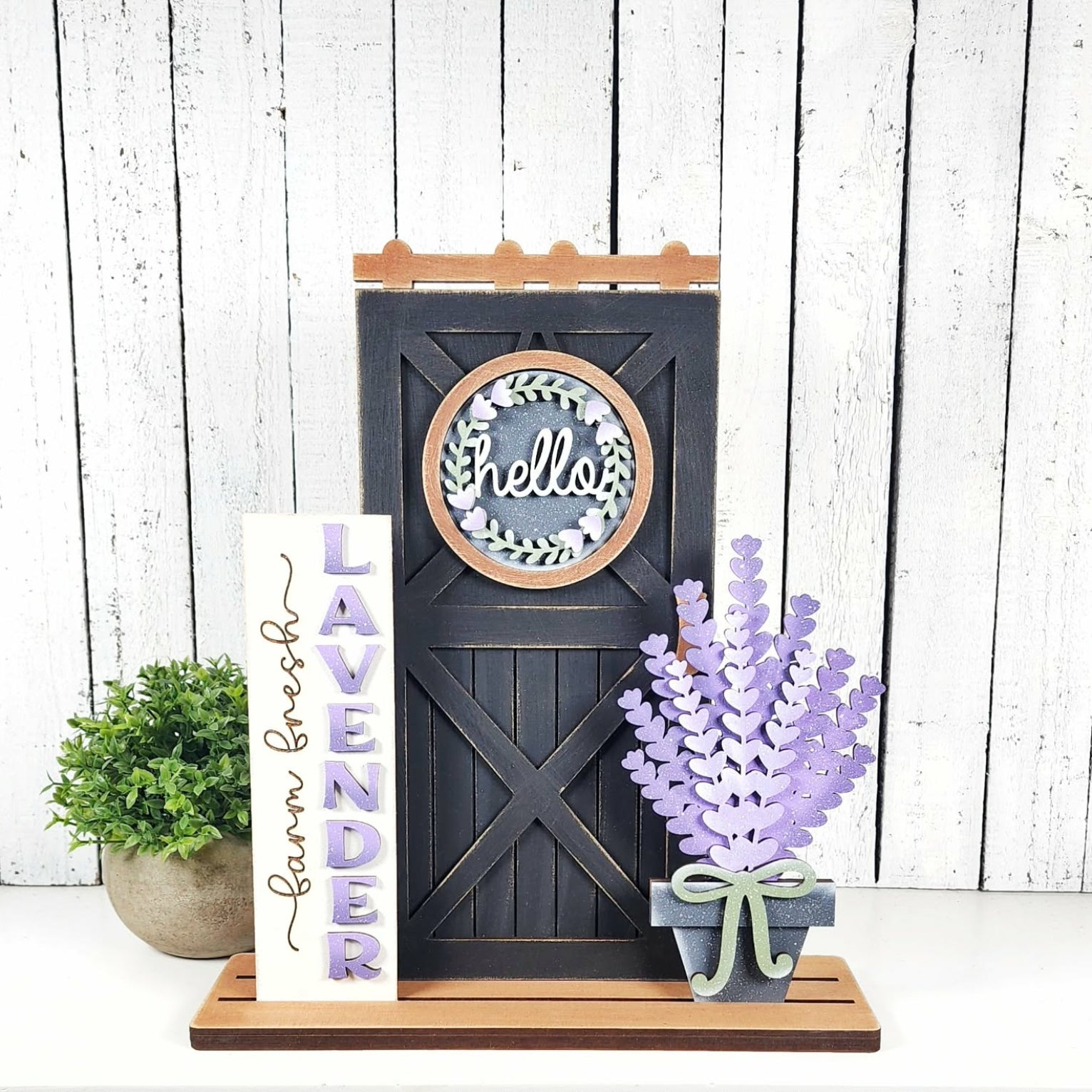 Decorative sign with 'hello' and wreath design, lavender plant, and 'Lavender Farm Fresh' sign on a wooden stand.