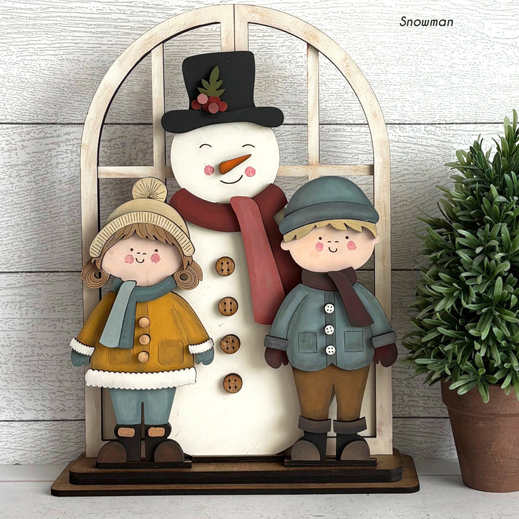 Decorative wall art with a snowman and two children on a wooden stand.
