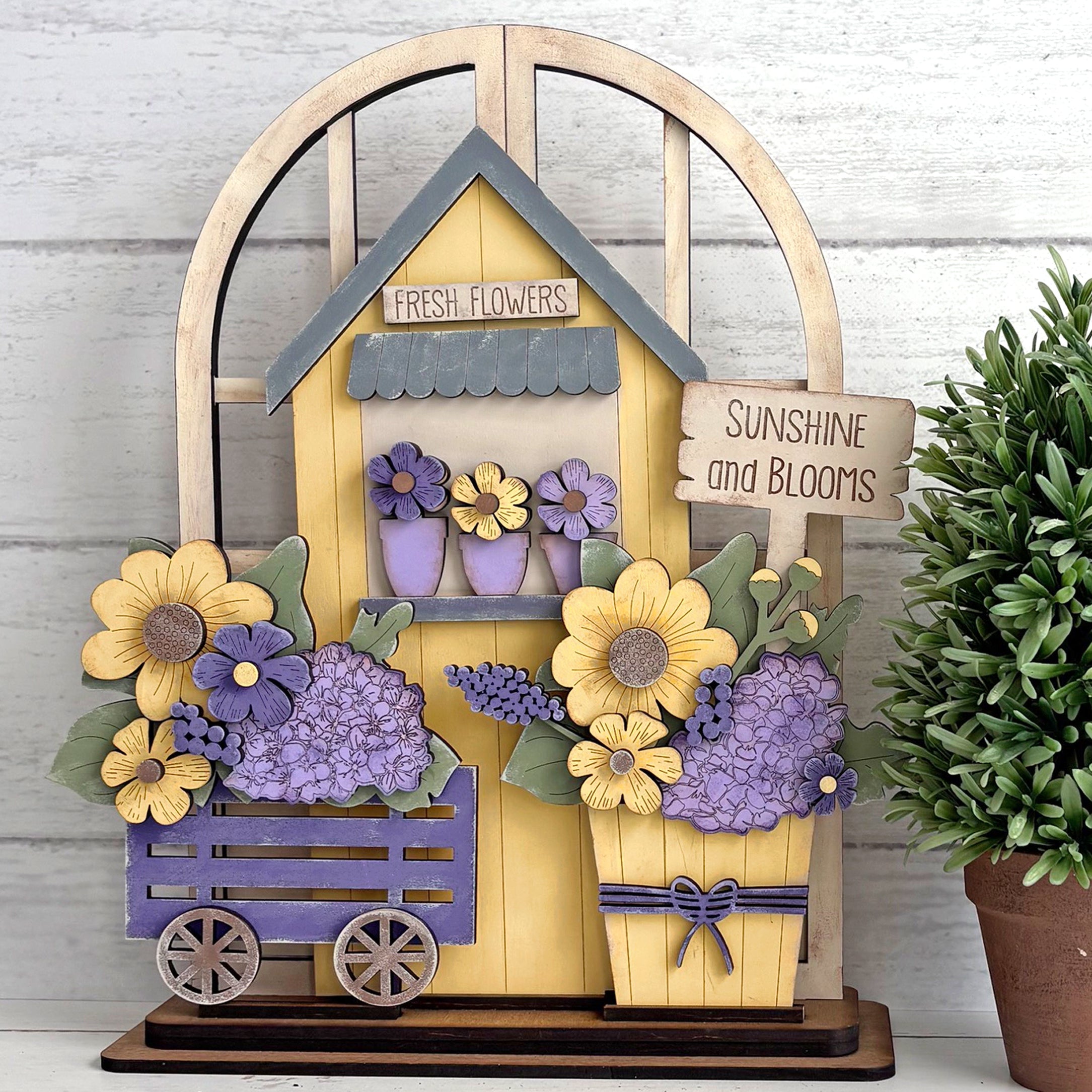 Decorative wooden flower stand with flowers and a pot on a white background
