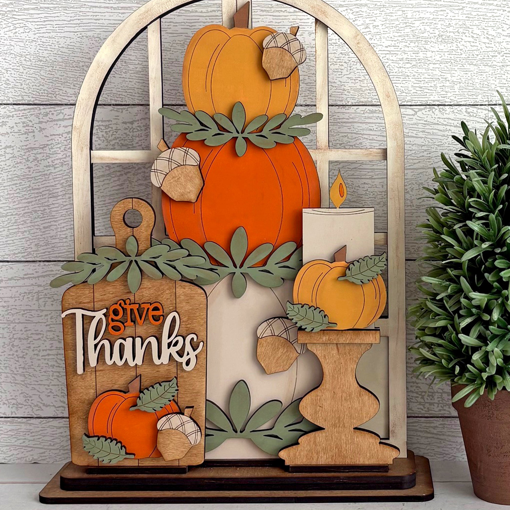 Decorative wooden sign with pumpkins and 'give Thanks' text on a wooden stand.