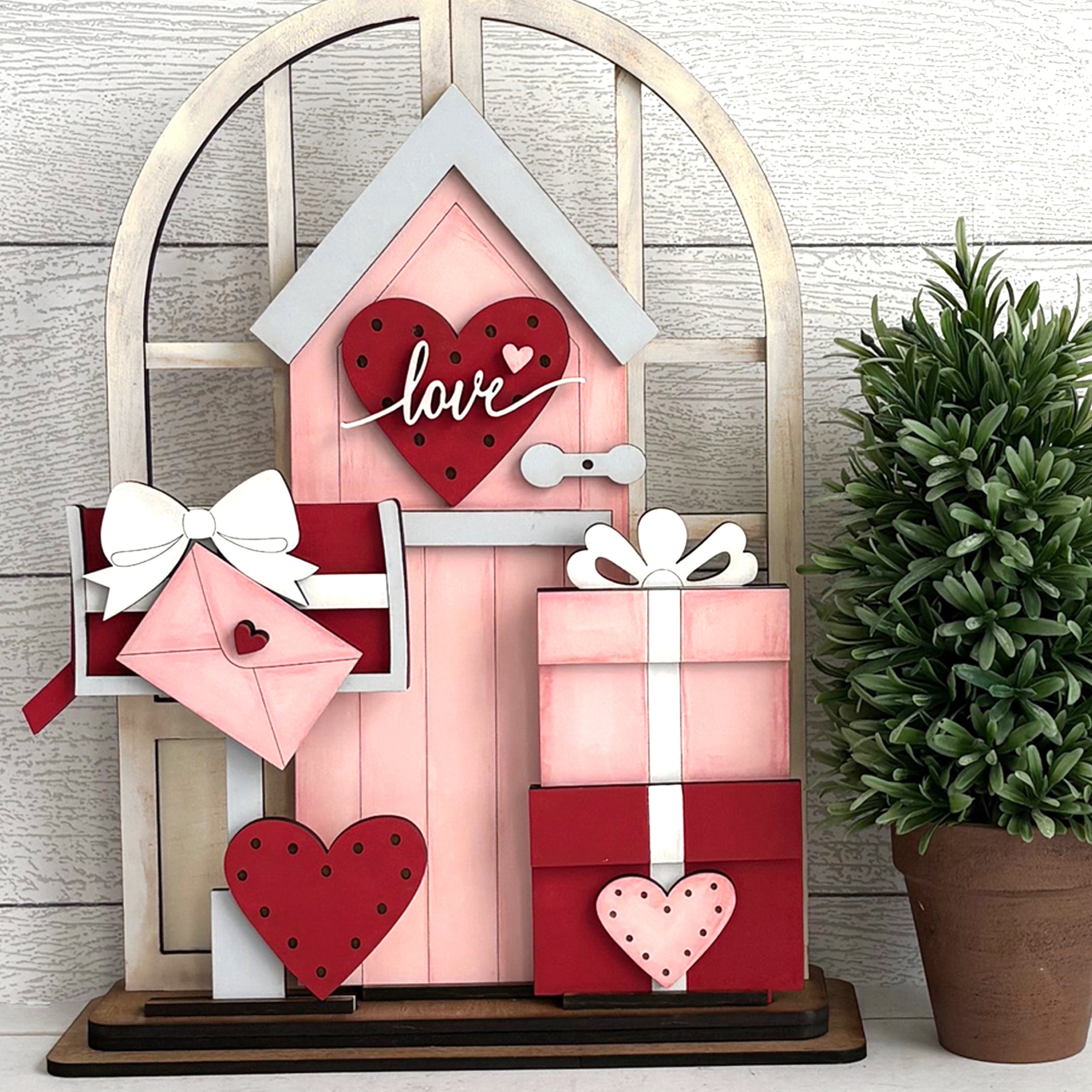 Decorative wooden house with hearts and gift boxes on a wooden background