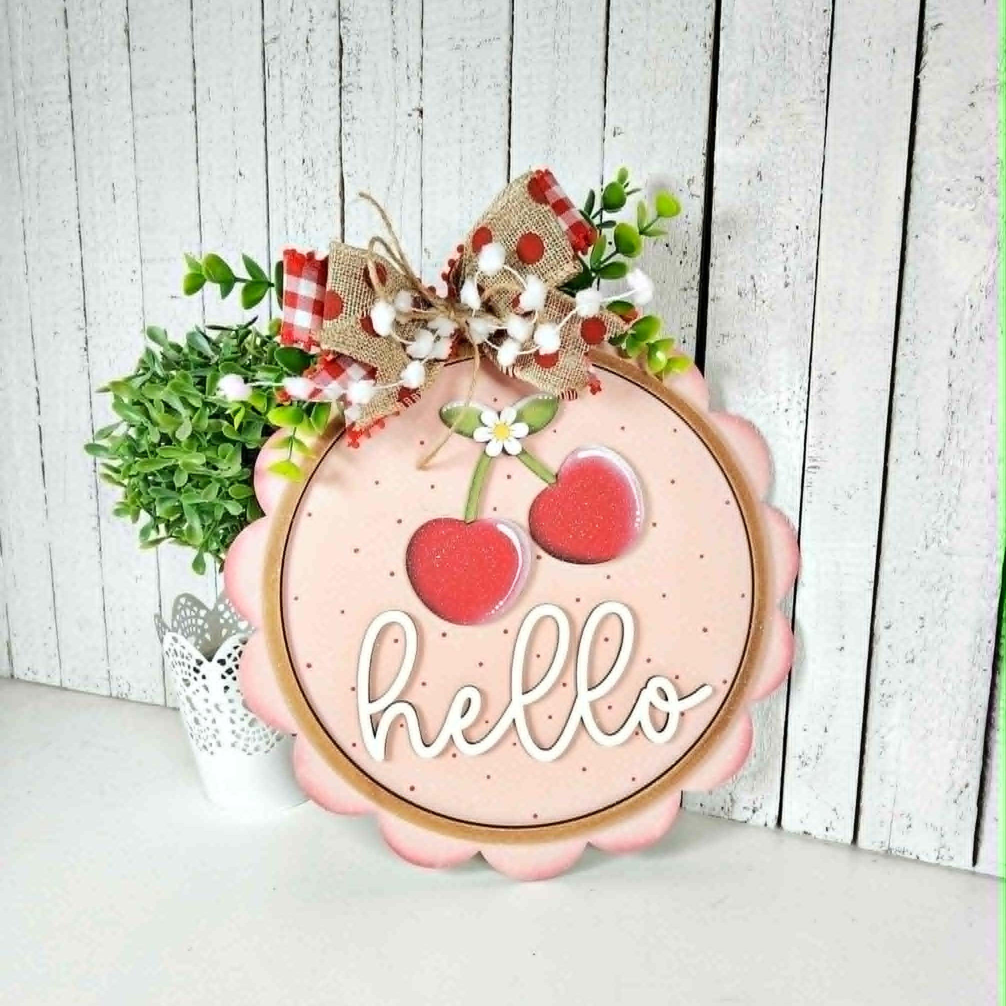 Decorative sign with cherries and 'hello' text on a wooden background