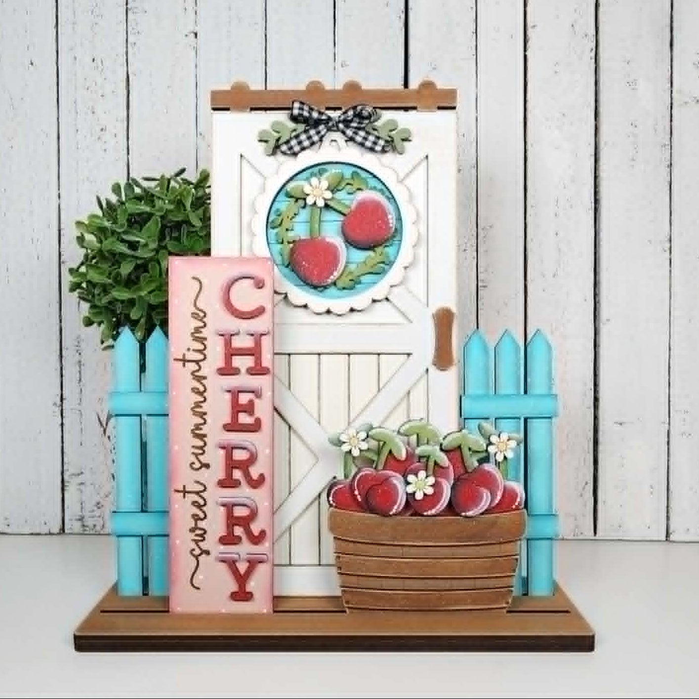 Decorative set with cherry-themed elements including a door, basket, and sign on a white wooden background.